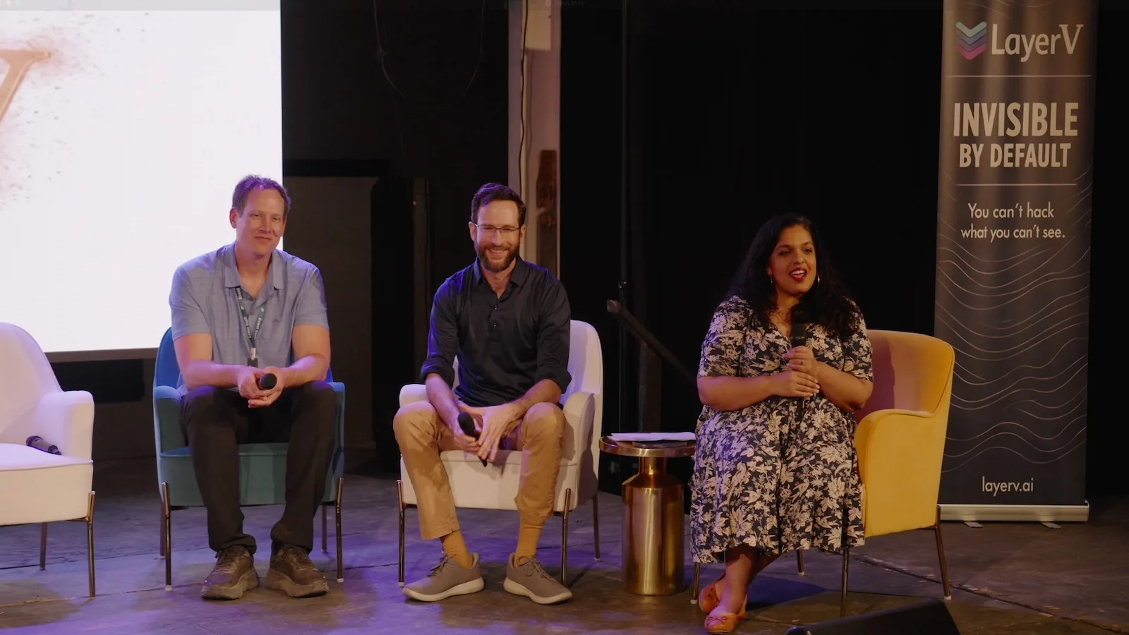 Joe Ollis, Justin Posey, and host Art Chandrasekaran on stage at Seekers Summit, in front of a LayerV banner reading 'Invisible by Default — You can't hack what you can't see.'